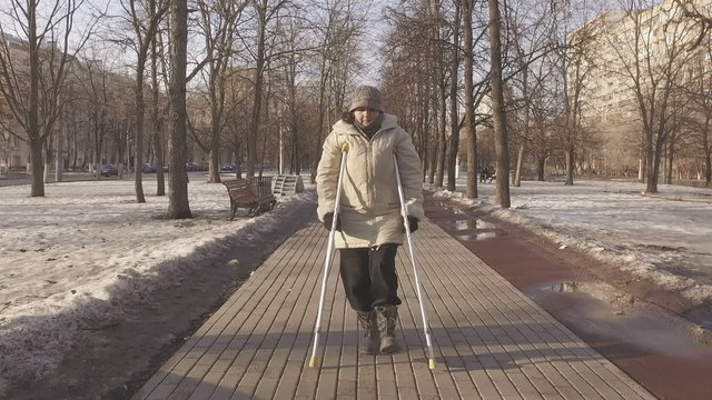 Mature woman on crutches in a city park