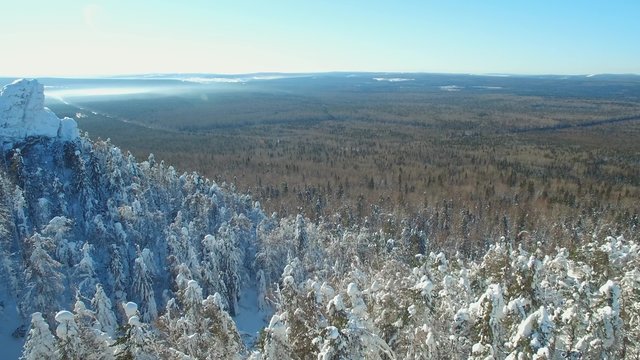 approximation to the lonely rock in the middle of a thick winter forest. aerial 4k video