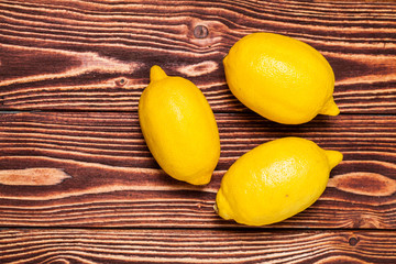 Top view of freshly whole lemons on rustic wooden background.