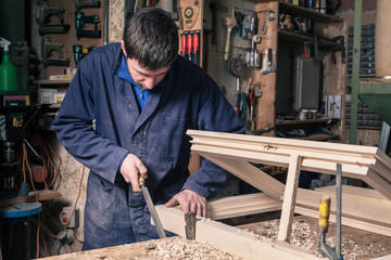 Carpenter working on a Wooden Window Frame with a File