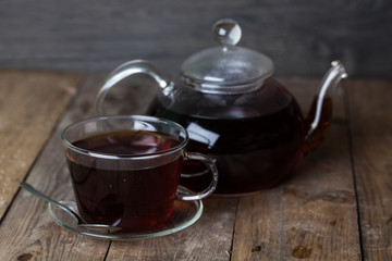 glass teapot and cup of tea on the wooden background