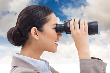 Composite image of businesswoman looking through binocular