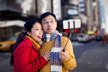 Composite image of older asian couple on balcony taking selfie