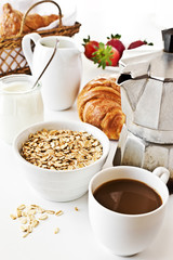 Breakfast with coffee, yogurt, oatmeal, croissant and strawberry.