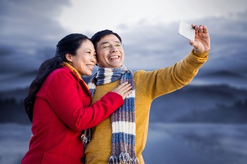 Composite image of older asian couple on balcony taking selfie