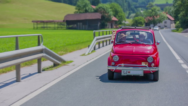 Old couple driving in a red zastava car