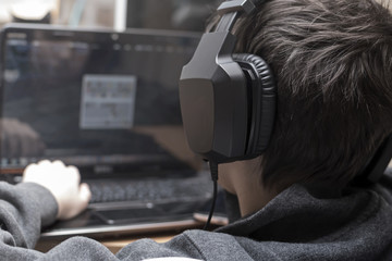 Teen boy with headphones and laptop 