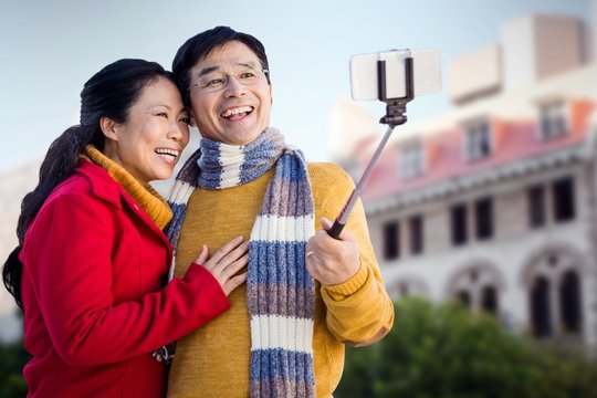 Composite Image Of Older Asian Couple On Balcony Taking Selfie