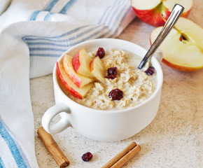 Oatmeal porridge with apples and cinnamon on marble table
