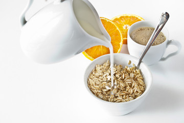 Breakfast - milk, oatmeal,sliced of orange on white.
