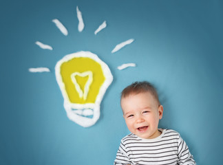 One year old boy and a bulb near. Child with an idea