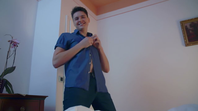 A young man dancing while unbuttoning his shirt
