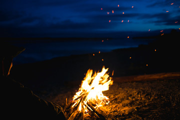 the silhouette of girl tourist around the campfire at night on the river shore