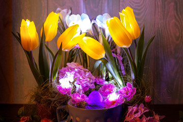 Easter composition of glowing in the dark, fresh tulips and colored eggs on a dark background