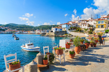 Fototapeta na wymiar Flower pots on and view of fishing boats anchoring in Kokkari bay, Samos island, Greece