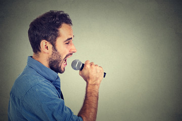 Singing man isolated on gray wall background