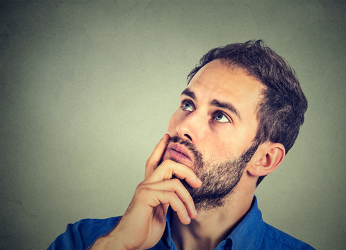 man resting chin on hand thinking daydreaming, staring thoughtfully upwards