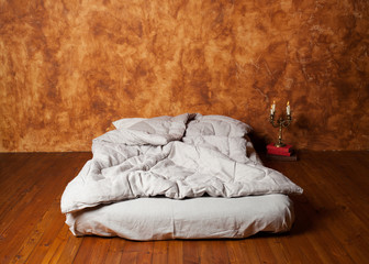  Empty room in the loft with a mattress as a bed, brown wall, wo
