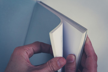 hands turning pages in empty book with blank pages