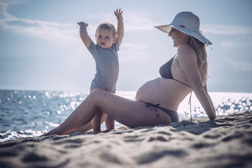 Caucasian boy and his expectant mother on beach