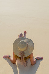 Fototapeta na wymiar Woman with hat laying on the beach