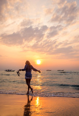 Fototapeta na wymiar carefree woman dancing in the sunset on the beach