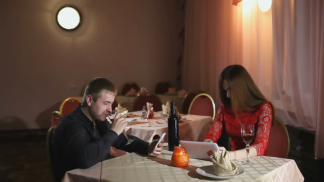 man and  girl with smartphone and tablet in a cafe romantic evening