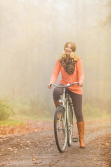 Naklejka premium Happy active woman riding bike in autumn park.