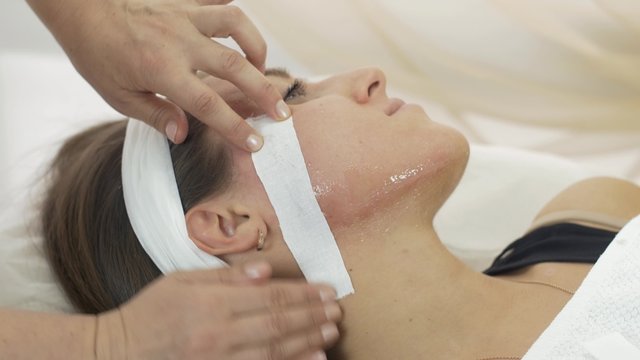 Close up of professional cosmetologist hands make epilation of girl chin and neck in beauty saloon. Cosmetic procedure