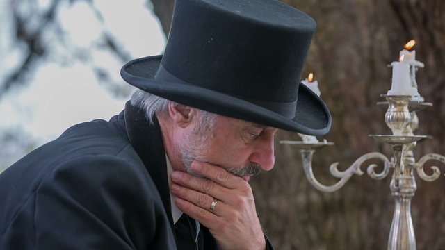 Man with cylinder on his had seating on the garden