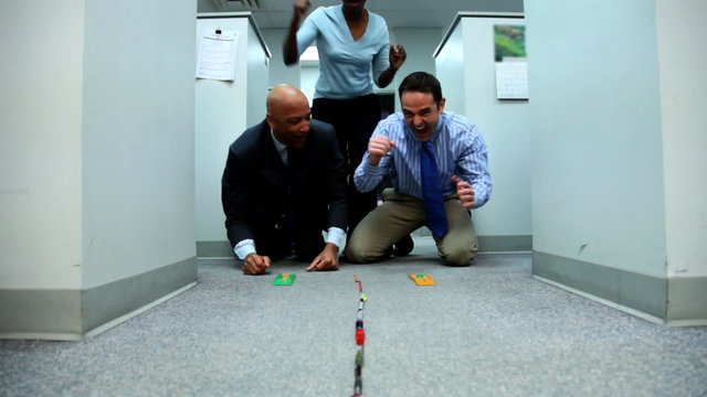Businesspeople racing toy cars in office