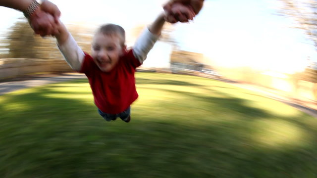 Young boy spinning around in parent's hands
