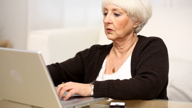 Senior woman using laptop and cell phone