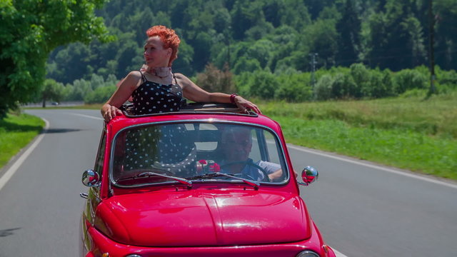 A senior lady observing the landscape when driving in a red yugo