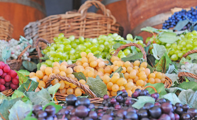 a display with a variety of sorts of grapes in red, green, blue, purple, yellow and orange in wooden baskets. Selective focus