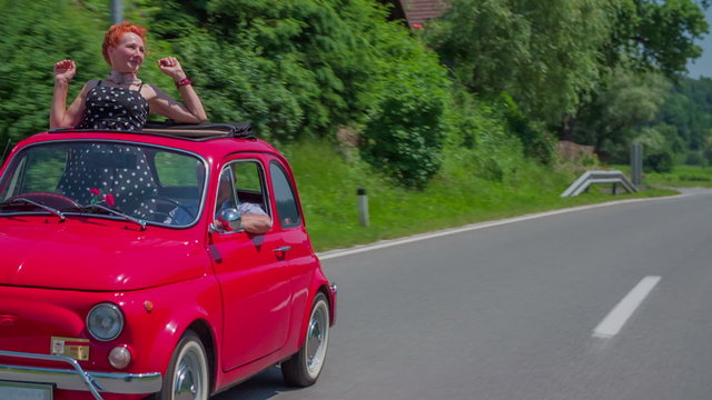 Red retro car driving on a country road