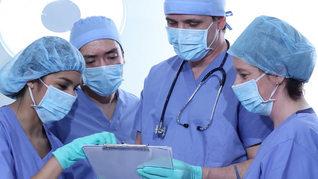 Group of surgeons in scrubs looking at clipboard