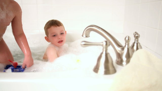 Playing with toy boats in bubble bath
