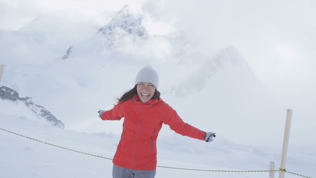 Happy woman having fun throwing snow Jungfrau alps Switzerland next to Aletsch glacier. Snow in summer in the Swiss alps. Female hiker looking at camera.