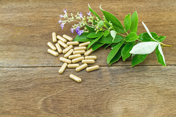 Close up fresh flower Vitex trifolia Linn or Indian Privet with pills on wooden background