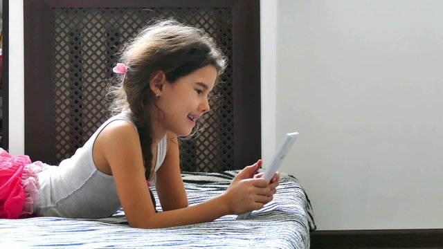 girl teen  playing tablet game internet sitting on bed