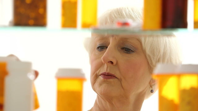 Senior woman looking for pills in medicine cabinet