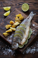 Baked trout fish with potato on a rustic wooden serving board