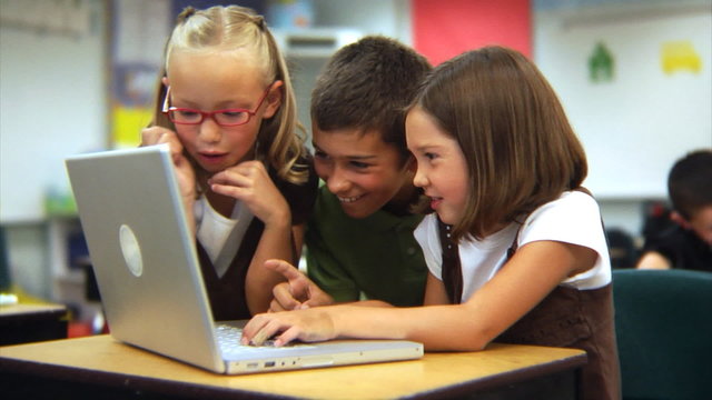 Elementary school students looking at laptop computer