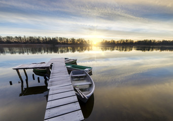 Łódka przy drewnianym pomoście nad jeziorem © Mike Mareen