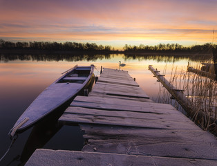 Łódka przy drewnianym pomoście nad jeziorem