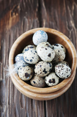 Uncooked quail eggs in the wooden bowl