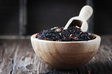 Delicious black tea with petals on the wooden table