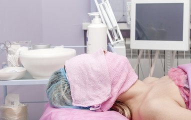 Obraz na płótnie Canvas Woman in a beauty salon with a towel on his face