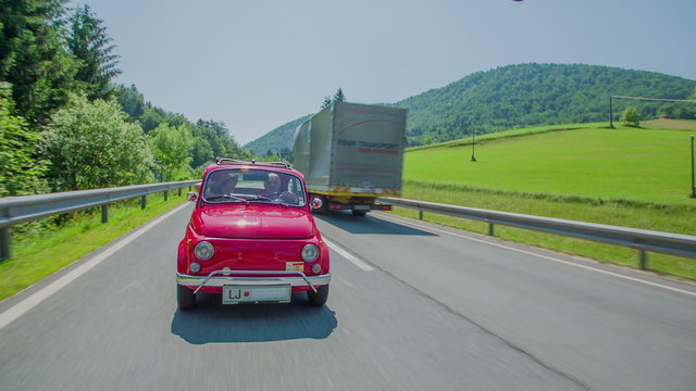 Red zastava driving on a main road and a truck passes him